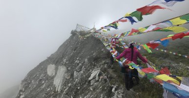 Woman climbing mountain with prayer flags, Photo: Austin Lord
