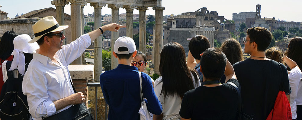 Man leading a tour in Rome in front of ruins
