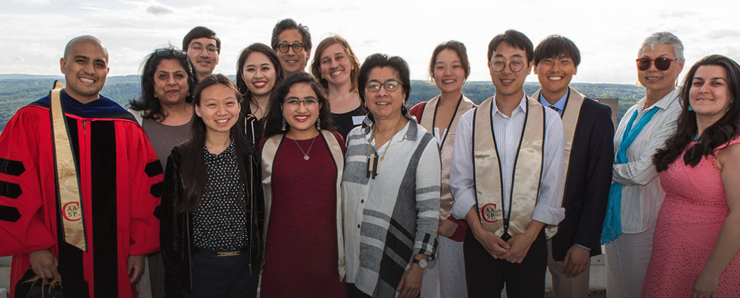 Students and faculty posing with students wearing graduation regalia
