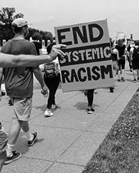 Young boy on man's shoulders holding a sign that says respect my life