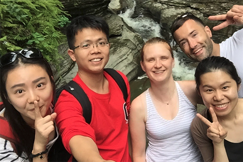 Five smiling students standing infront of a waterfall