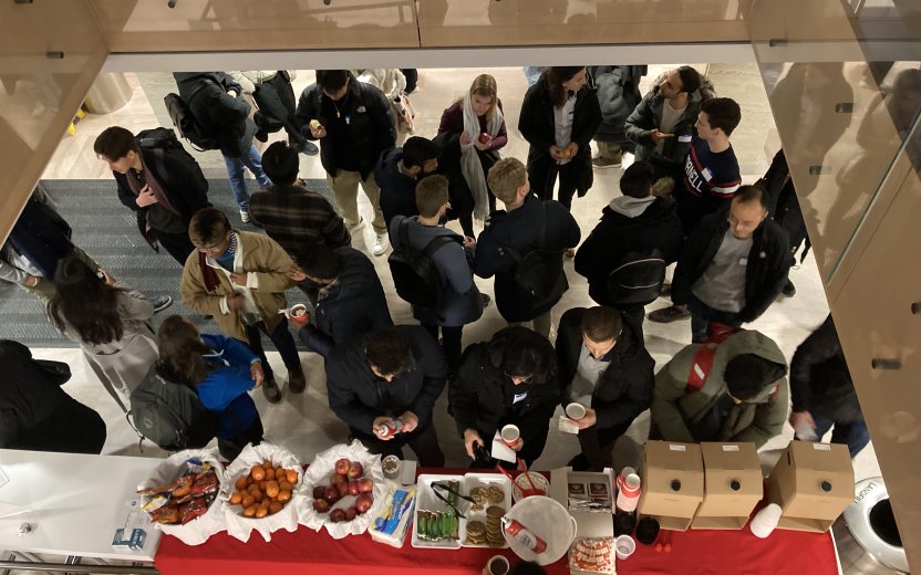 Birdseye view of students socializing around a refreshment table. 