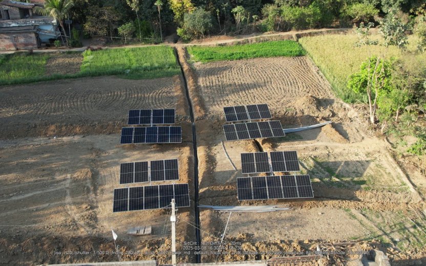 An array of solar panels in a farm field.