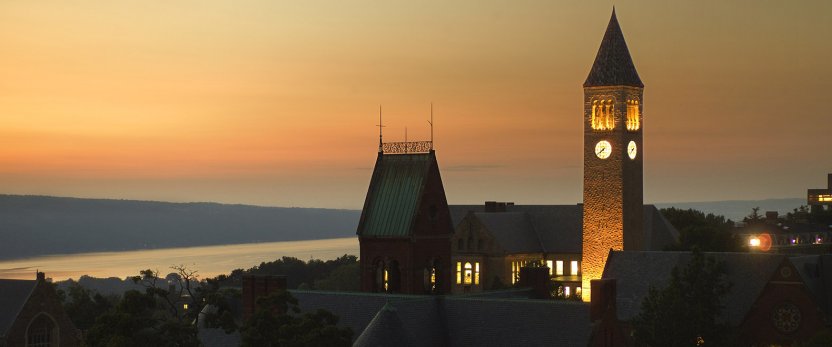 Sunset over Cornell's campus with McGraw Clock Tower lit and the lake in the background.