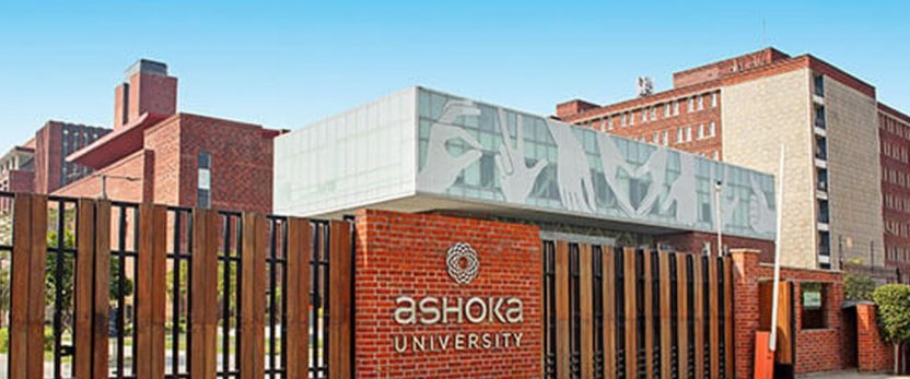 Buildings behind a fence with a sign that reads Ashoka University.