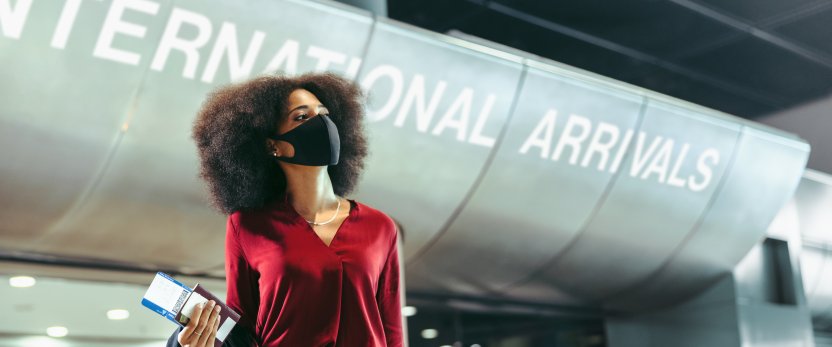 Woman with face mask on arrives at international airport.
