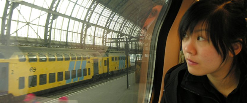 Student holding a map looking out of a train car at the station in Amsterdam.