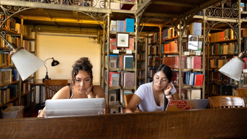 Two students sitting at a desk in the AD White Library.