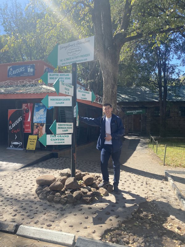 Charles Chen standing in front of a post with several directional signs affixed..