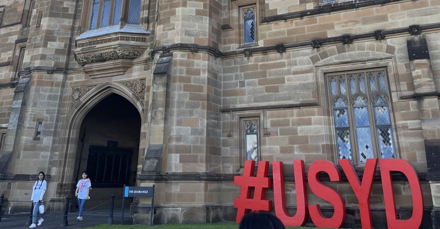 Stone building with a large red #USYD sign in front.