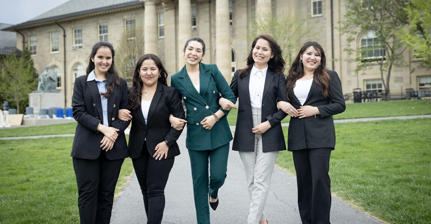 Five graduating Afghan students link arms and walk together on campus.