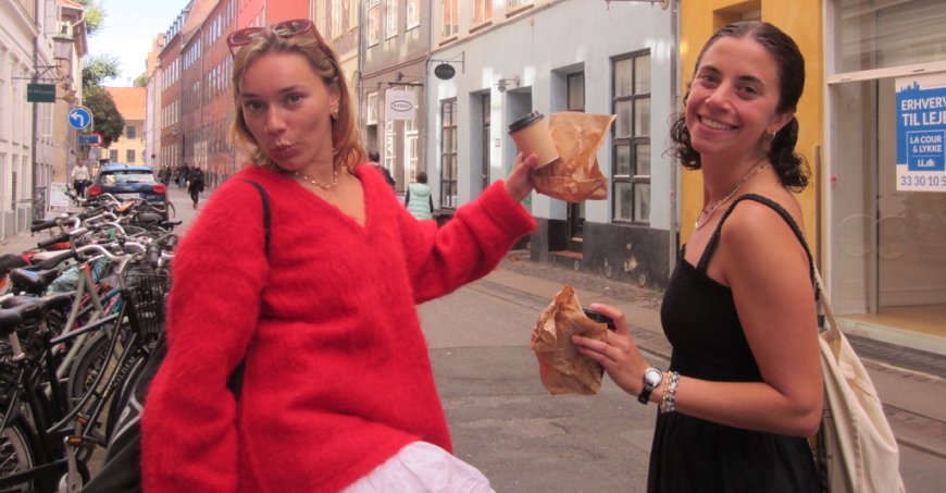 Rebecca Herzberg holds coffee and a pastry with a friend in Copenhagen.