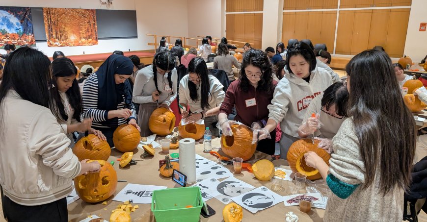 Students gathered around tables carving pumpkins.