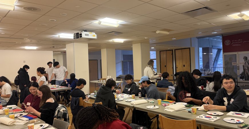 Students sitting at long tables painting on canvases.