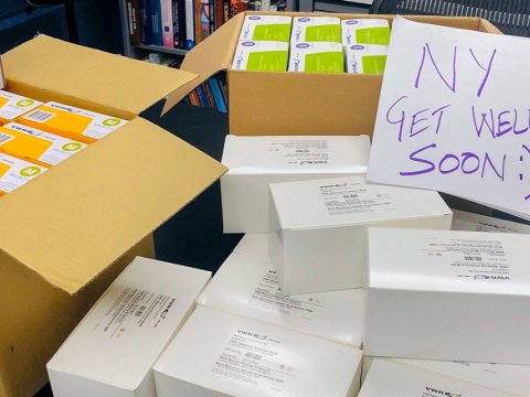 Boxes of medical supplies with a handwritten sign that reads, NY get well soon.