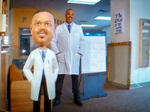 Video clip of a doctor wearing a lab coat standing next to a caricature of himself