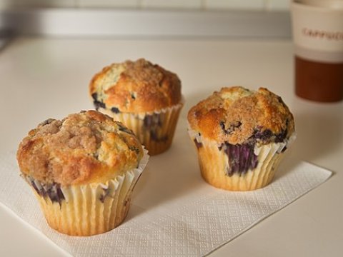Three blueberry muffins on parchment paper