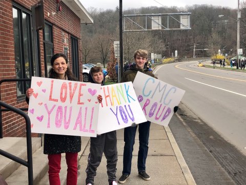 Mother and two sons holding hand-made signs about CMC