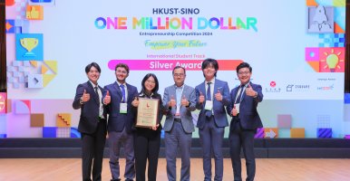 Five students and their host stand in front of a screen announcing their silver award. 