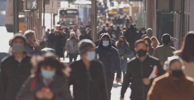 Anonymous crowd of people walking street wearing masks during Covid-19 pandemic.