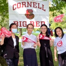 International students on campus stand in front of "Cornell Big Red" sign