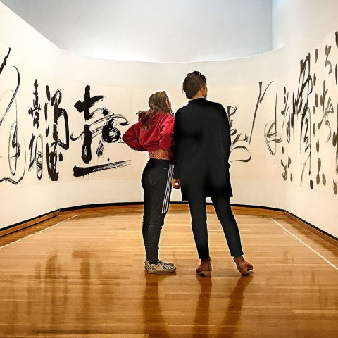 Two museum visitors looking at a wrap-around canvas of Asian characters