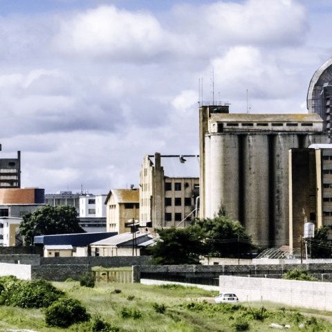 Lusaka skyline with tall buildings and cinderblock walls in the foreground.