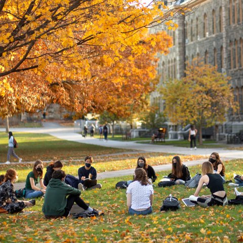 A circle of students sitting on the Arts Quad.