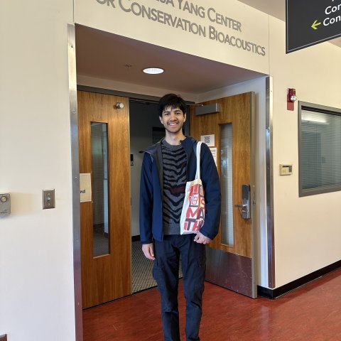 Neel Le Penru smiles for a photo in front of the Lab of Ornithology.